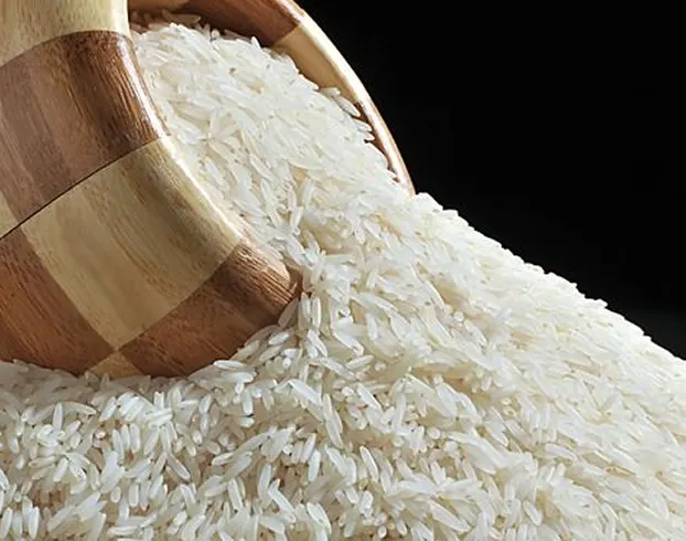 White rice grains spilling from a wooden bowl